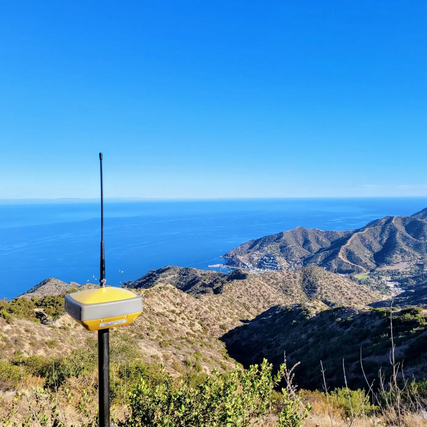 GNSS receiver on a pole high above Avalon harbor on Catalina Island, with the Pacific behind